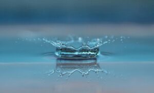 Macro shot of a water droplet creating a ripple effect on the water surface.
