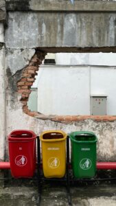 Colorful recycling bins placed against a weathered wall in Jakarta, Indonesia.