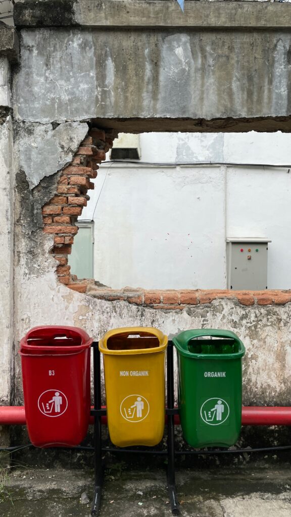 Colorful recycling bins placed against a weathered wall in Jakarta, Indonesia.