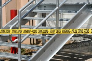 Close-up of a metal stairway blocked by yellow police crime scene tape outdoors.
