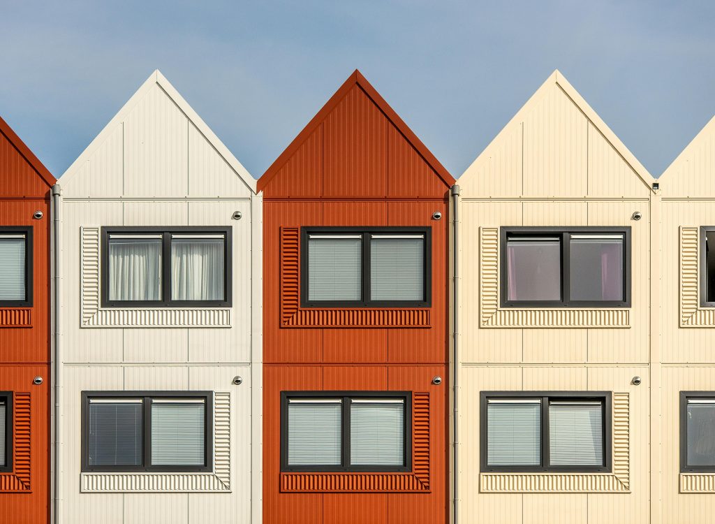 Contemporary row houses with vibrant color palette under a clear sky, showcasing modern architecture.