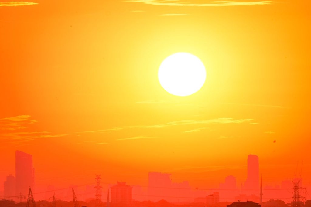 A city skyline silhouetted against a vivid, orange sunset sky.