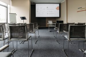An empty conference room with chairs, a projector screen, and presentation setup.